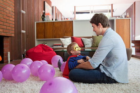 Father and son playing with balloons in living roomの写真素材