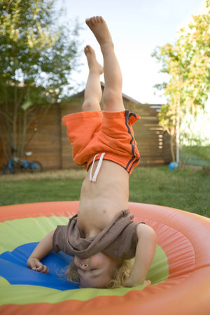 Young boy doing headstand on trampolineの写真素材