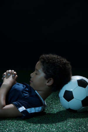 Boy sleeping with football as pillow