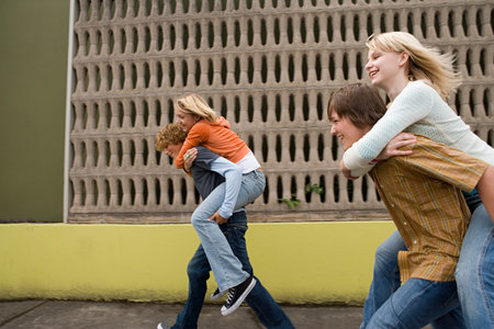 Four teenagers running piggy back racesの写真素材