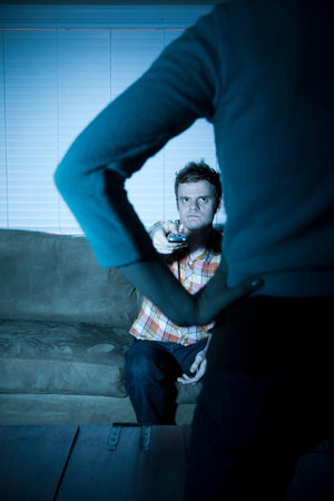 Young man watching tv, woman blocking viewの写真素材