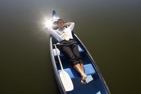 Businessman asleep in canoe.の写真素材
