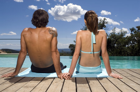 Couple sunbathing by a swimming poolの写真素材