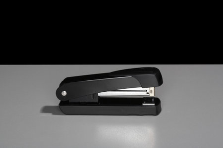 Black stapler sitting on a table.の写真素材