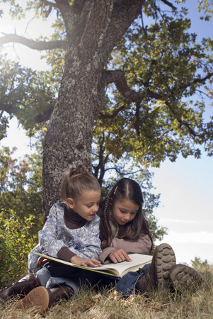 Two young girls reading a bookの写真素材