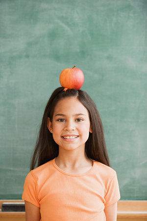 Schoolgirl balancing an apple on her headの写真素材