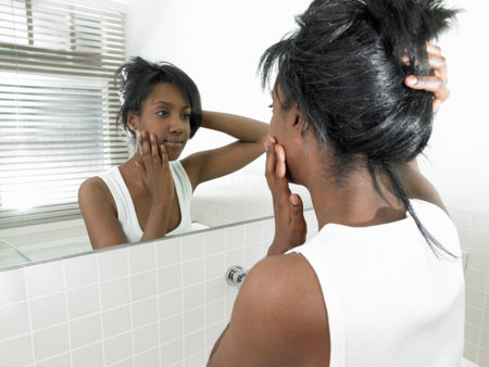 Woman in bathroom, looking in the mirrorの写真素材