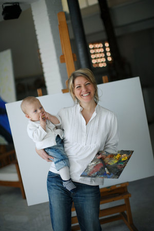 Mother holding baby in front of easelの写真素材