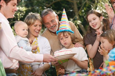 Young boy blowing out candles at partyの写真素材