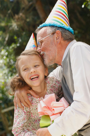 Grandfather kissing grandchild at partyの写真素材