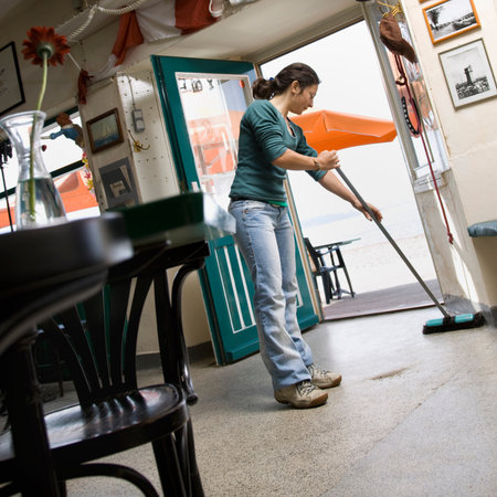 Woman sweeping in a cafeの写真素材