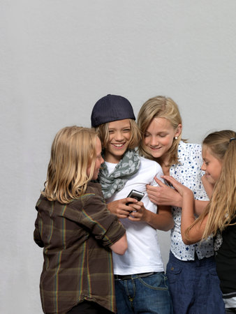 Four kids with mobile phoneの写真素材
