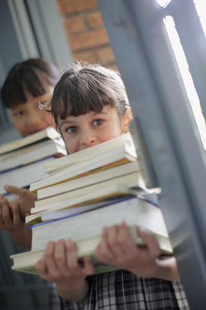 School girls holding stacks of booksの写真素材