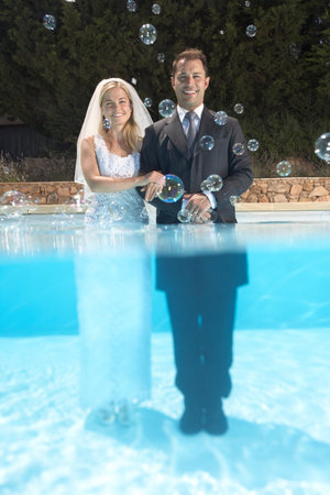 Bride and groom in pool with bubblesの写真素材