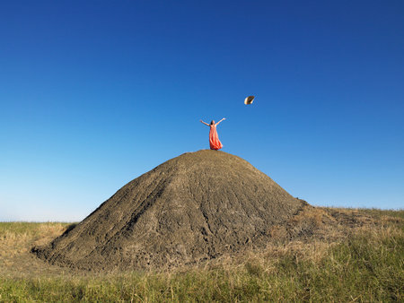 Woman on top of hill throwing hat