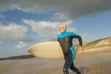 Male running into sea with a surfboardの写真素材