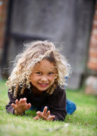 Young girl crawls on grass toward cameraの写真素材