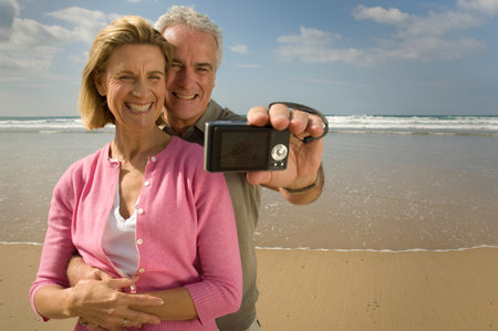 Couple taking photograph on a beachの写真素材