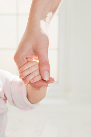 A mothers hand holding her baby's hand.の写真素材