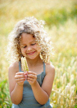 Young girl with ears of corn in fieldの写真素材