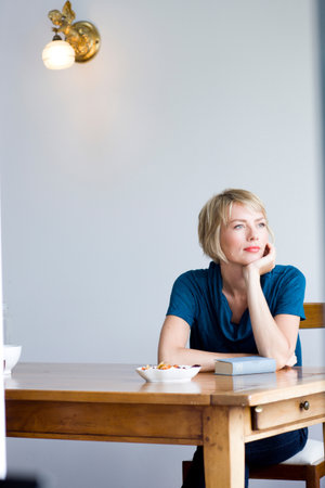 Woman at table looking into distanceの写真素材