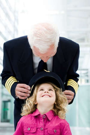 Flight captain fitting hat onto girlの写真素材
