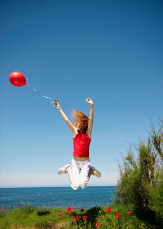 Young girl jumping with red balloonの写真素材