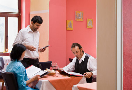 Waiter taking orders from customersの写真素材