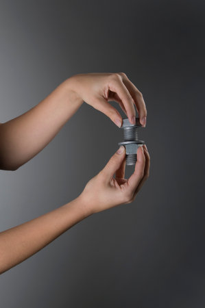 Female hands holding nut and boltの写真素材