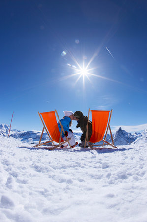 Couple kissing/reclining in deck chairsの写真素材