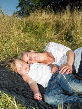 Mother and daughter sleeping in a fieldの写真素材
