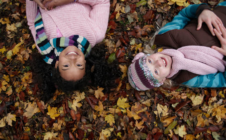 Two friends lying on autumn leavesの写真素材