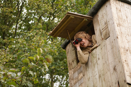 Boy with binoculars in treehouseの写真素材