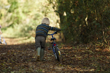 Boy walking bike in countrysideの写真素材
