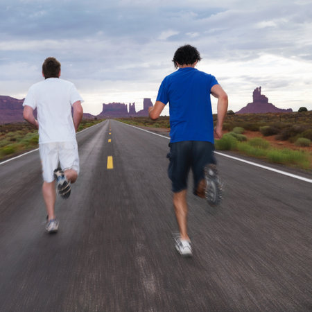 Two men jogging on road in desertの写真素材