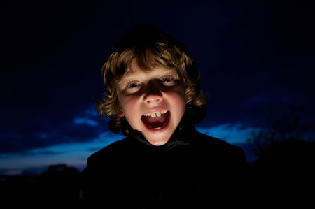 Boy making faces with flashlightの写真素材