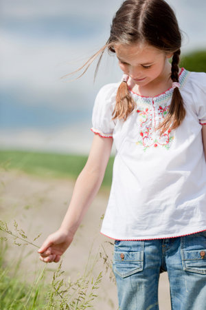 young girl playing with grassの写真素材