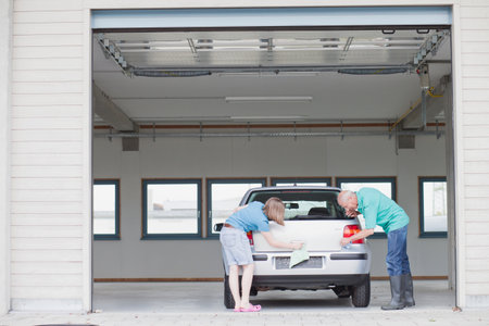 old man and young girl washing carの写真素材