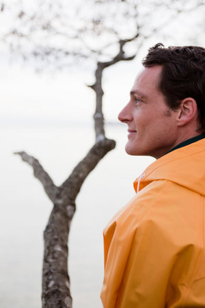 man in raincoat looking on a lake