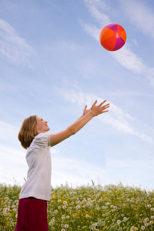 Girl in meadow playing ballの写真素材