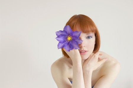 woman holding flower in front of eyeの写真素材