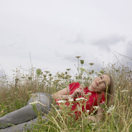 Young woman lying in high grass and flowerの写真素材