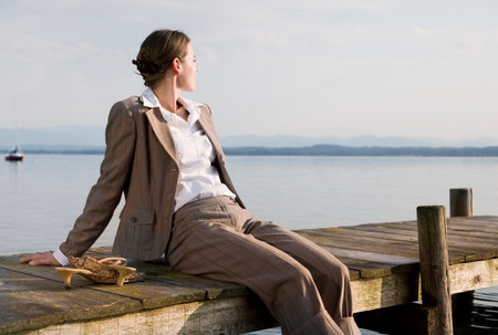 woman sitting on pier at lakeの写真素材