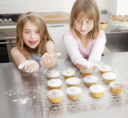 Two girls baking with icing sugarの写真素材