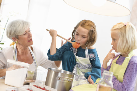 girls with grandmother cooking jamの写真素材