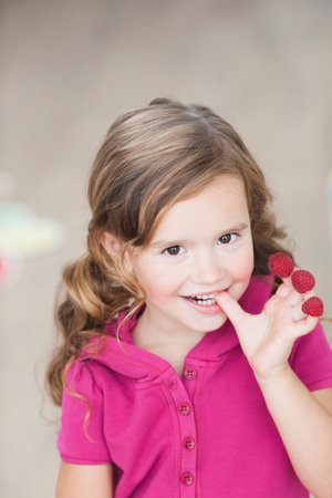 young girl eating berries from fingersの写真素材