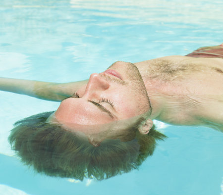 young man floating in waterの写真素材