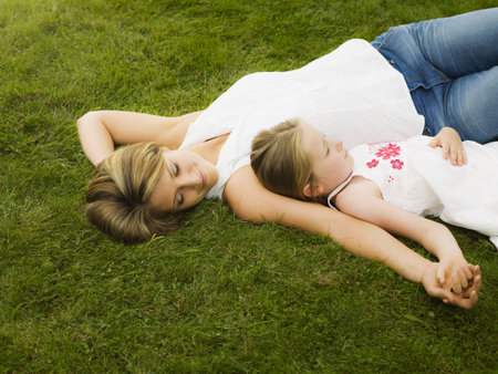 A mother and daughter lying on a lawnの写真素材