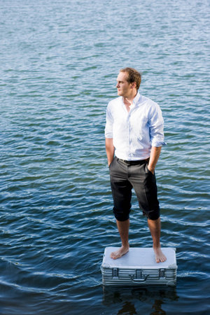 man standing on floating suitcaseの写真素材