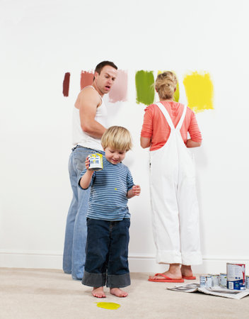 Toddler boy pouring paint onto carpetの写真素材